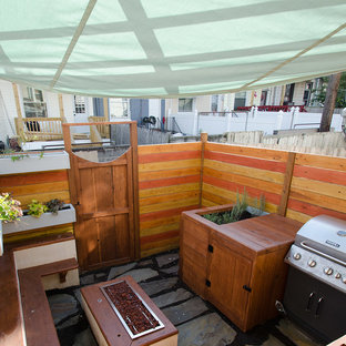 Ispirazione per un piccolo patio o portico american style dietro casa con un focolare, pavimentazioni in pietra naturale e un parasole