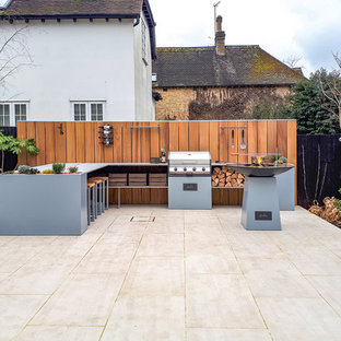 Photo of a medium sized contemporary back patio in Kent with an outdoor kitchen, no cover and natural stone paving.