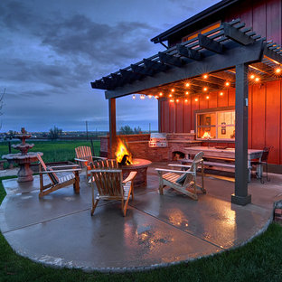 Esempio di un patio o portico country con un focolare, pavimentazioni in cemento e una pergola