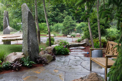 Example of a large mountain style backyard stone patio design in Boston with no cover