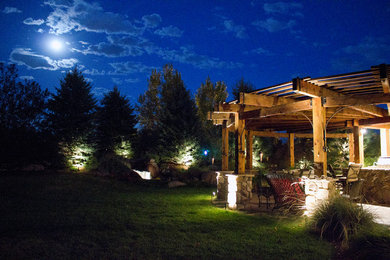 Example of a large mountain style backyard stone patio design in Denver with a pergola