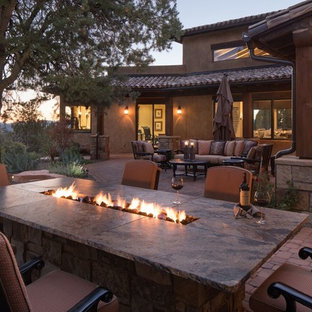 Esempio di un grande patio o portico stile americano dietro casa con un focolare, pavimentazioni in pietra naturale e un tetto a sbalzo