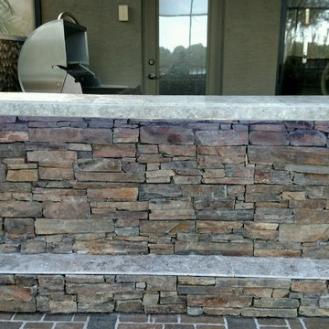 Rustic stacked stone L shaped kitchen with Green Egg