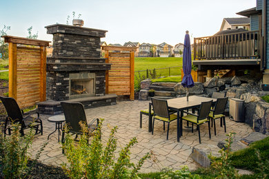 Example of a large trendy backyard brick patio fountain design in Calgary with no cover