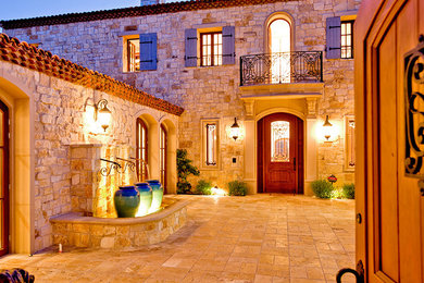 Example of a farmhouse courtyard stone patio fountain design in Orange County with no cover