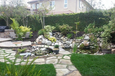 Modelo de jardín clásico renovado de tamaño medio en patio trasero con adoquines de piedra natural
