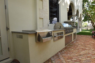 Example of a tuscan backyard brick patio kitchen design in Miami with no cover