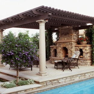 Immagine di un patio o portico mediterraneo di medie dimensioni e dietro casa con un focolare, lastre di cemento e una pergola