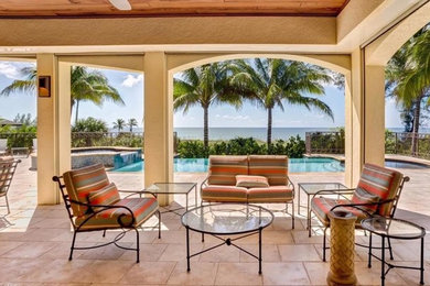 マイアミにあるラグジュアリーな巨大な地中海スタイルのおしゃれな裏庭のテラス (噴水、天然石敷き、張り出し屋根) の写真