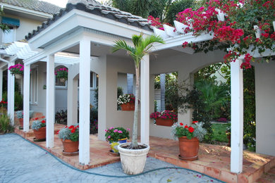 Large beach style backyard concrete paver patio photo in Miami with a gazebo