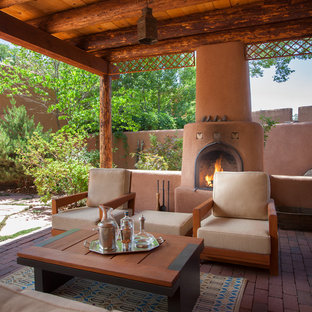 Foto di un patio o portico stile americano con un focolare, pavimentazioni in mattoni e una pergola