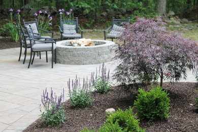 Example of a mid-sized classic backyard stone patio design in New York with a fire pit and no cover