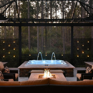 Immagine di un patio o portico tropicale dietro casa e di medie dimensioni con una pergola, un focolare e piastrelle