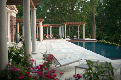 Modelo de patio clásico renovado grande en patio trasero con fuente, adoquines de piedra natural y pérgola