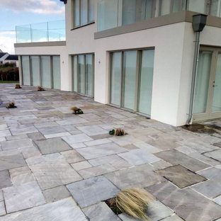 Idee per un grande patio o portico scandinavo dietro casa con pavimentazioni in pietra naturale