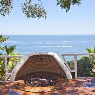 Immagine di un patio o portico mediterraneo dietro casa con un focolare, piastrelle e nessuna copertura