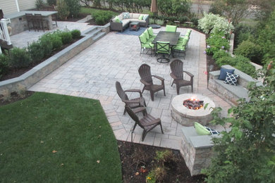 Example of a large classic backyard stone patio design in New York with a fire pit and no cover