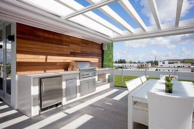 Mid-sized trendy backyard concrete paver patio kitchen photo in Miami with a pergola