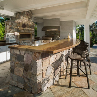 Large transitional backyard stone patio kitchen photo in New York with a pergola