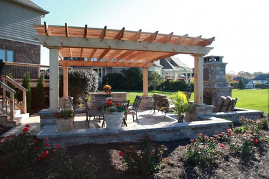 Diseño de patio clásico grande en patio trasero con brasero, adoquines de ladrillo y pérgola