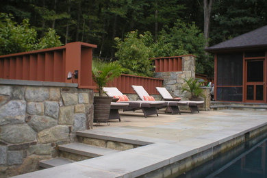 Example of a mid-sized mountain style backyard stone patio fountain design in DC Metro with a pergola