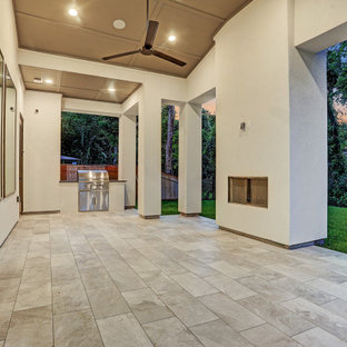 Foto di un ampio patio o portico chic dietro casa con un caminetto, piastrelle e un tetto a sbalzo