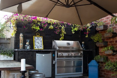 Ejemplo de patio de estilo americano de tamaño medio en patio trasero con cocina exterior, entablado y toldo