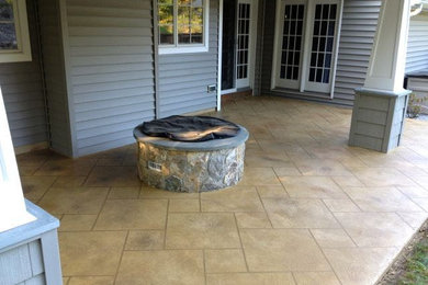 Cette photo montre une grande terrasse arrière tendance avec un foyer extérieur, des pavés en béton et une extension de toiture.