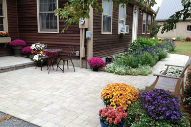 Example of a mid-sized cottage front yard concrete paver patio design in Burlington with no cover