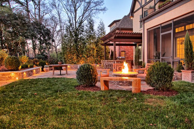 Example of a mid-sized classic backyard stone patio design in Charlotte with a fire pit and a pergola