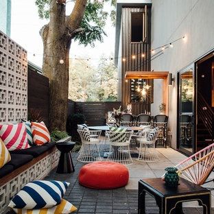 Foto di un patio o portico eclettico di medie dimensioni e dietro casa con pavimentazioni in mattoni e un parasole