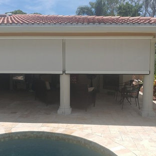 Foto di un patio o portico tropicale di medie dimensioni e dietro casa con piastrelle e un tetto a sbalzo