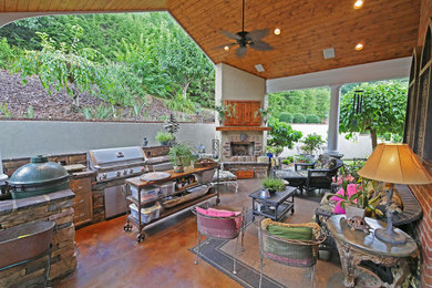 Example of a large classic backyard stamped concrete patio kitchen design in Other with a roof extension