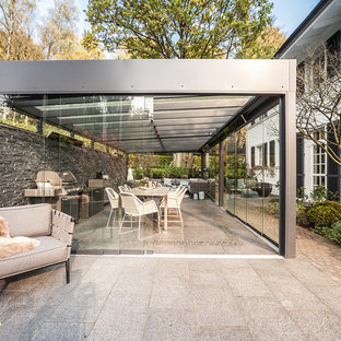 Großer Moderner Patio hinter dem Haus mit Outdoor-Küche, Betonplatten und Gazebo in Hamburg