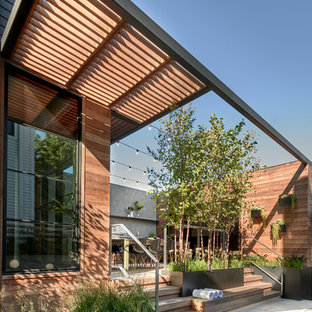 Foto di un piccolo patio o portico design nel cortile laterale con pavimentazioni in pietra naturale e una pergola