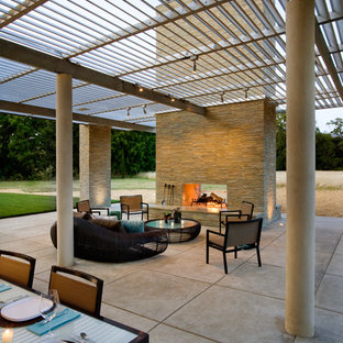 Ispirazione per un ampio patio o portico moderno dietro casa con un focolare, lastre di cemento e un tetto a sbalzo