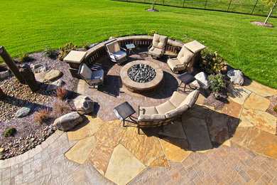 Example of a large backyard concrete paver patio design in Omaha with a fire pit