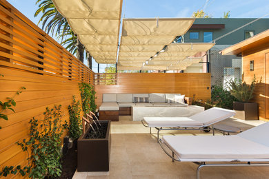 Ejemplo de patio moderno de tamaño medio con fuente, suelo de baldosas y toldo