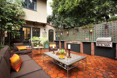 Photo of a mediterranean patio in Orange County with an outdoor kitchen, tiled flooring and no cover.