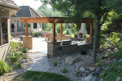Diseño de patio clásico en patio trasero con adoquines de hormigón, cocina exterior y pérgola