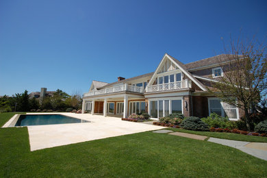 Example of a large beach style backyard tile patio design in New York with a roof extension