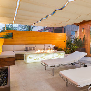 Inspiration for a mid-sized contemporary tile patio remodel in Los Angeles with a fire pit and an awning