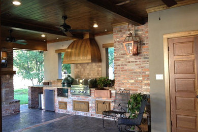 Large mountain style backyard stamped concrete patio kitchen photo in New Orleans with a roof extension