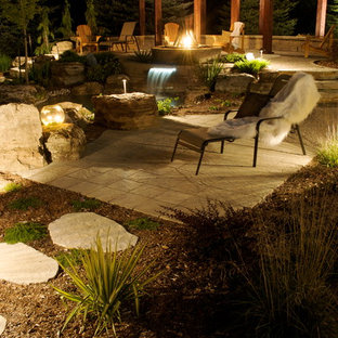 Immagine di un grande patio o portico etnico dietro casa con fontane, pavimentazioni in cemento e una pergola