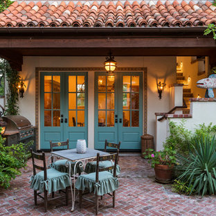 Esempio di un patio o portico mediterraneo di medie dimensioni e dietro casa con pavimentazioni in mattoni e un tetto a sbalzo