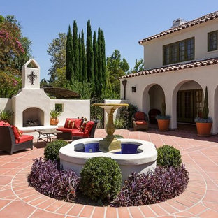 Immagine di un grande patio o portico dietro casa con un focolare, piastrelle e nessuna copertura