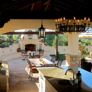 Foto di un patio o portico mediterraneo di medie dimensioni e dietro casa con pavimentazioni in pietra naturale, un gazebo o capanno e un caminetto
