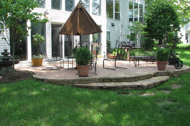 Imagen de patio clásico de tamaño medio sin cubierta en patio trasero con adoquines de piedra natural