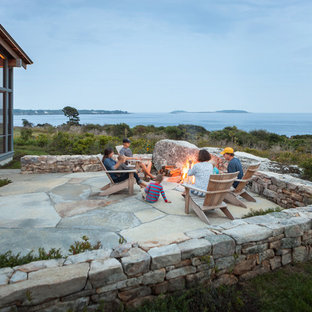 Immagine di un ampio patio o portico design dietro casa con un focolare, pavimentazioni in pietra naturale e nessuna copertura