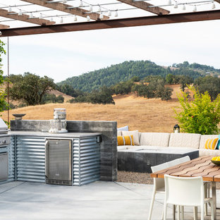 Esempio di un patio o portico country dietro casa con lastre di cemento e una pergola